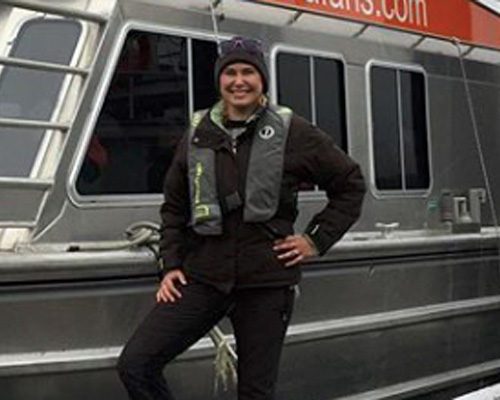 Tour guide wearing life jacket standing beside Westcoast Aquatic Safaris boat