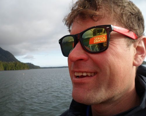 Smiling tour guest with Westcoast Aquatic Safaris sign reflected in sunglasses